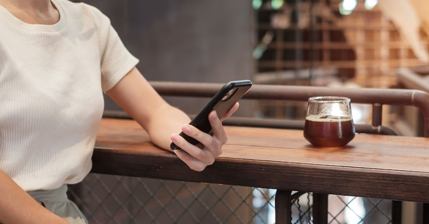 Woman holding a phone in a coffee shop.